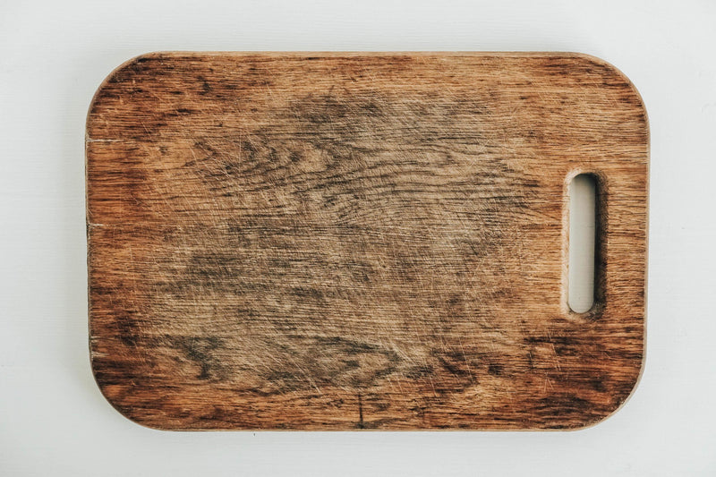 Wooden cutting board with a white handle on a light gray background